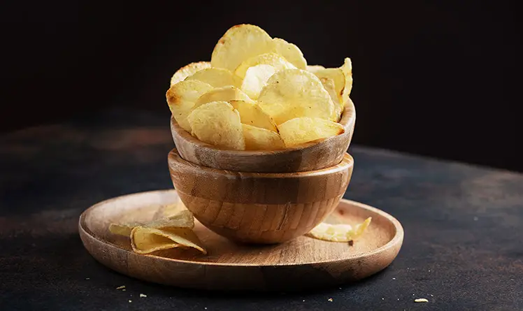 A bowl with fresh potato chips inside of it
