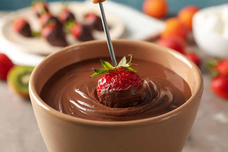 a strawberry being dipped in chocolate